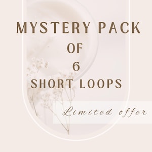 May include: A beige graphic with the text "MYSTERY PACK OF 6 SHORT LOOPS" in brown. The words are arranged vertically. The words "Limited offer" are written in a cursive font at the bottom. The background has a blurred floral design.