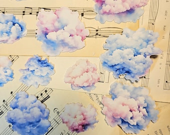 May include: A collection of watercolor painted cloud stickers in shades of blue, pink, and white. The stickers are arranged on a sheet of music with musical notes.