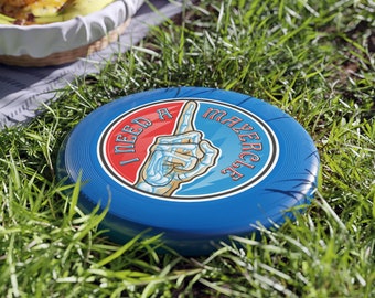 Può includere: Frisbee blu con un design circolare bianco e rosso. Il cerchio dice "I need a mayzercise" con una mano scheletrica che punta verso l'alto.
