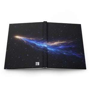 Op de afbeelding: Een hardcover notitieboek met een hemels ontwerp. De omslag heeft een donkerblauwe achtergrond met een levendige illustratie van een kosmische nevel in tinten blauw, goud en wit. De rug is zwart en het notitieboek is open.