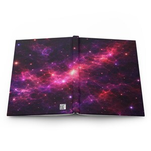 May include: Open journal with a vibrant galaxy design. The cover features a cosmic nebula in shades of purple, pink, and red, with numerous stars. The spine is black, and the journal is open, revealing the blank pages.