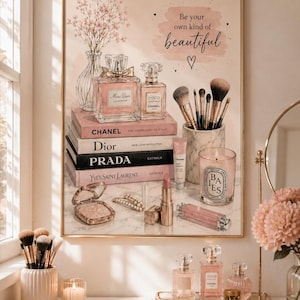 Op de afbeelding: Een ingelijste kunstdruk met een stapel modeboeken met de labels Chanel, Dior, Prada en Yves Saint Laurent. De afbeelding bevat parfumflesjes, make-upkwasten in een marmeren houder, een brandende kaars en cosmetica, met de tekst Be your own kind of beautiful.
