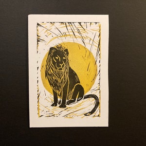 Impressão em bloco de leão com fundo de sol dourado. Imagem 10x15 cm. Artesanato artesanal, felino grande, arte animal. Disponível como cartão comemorativo ou impressão fosca.