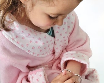 Pale pink children's bathrobe with floral cuffs.