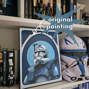 May include: An original painting of a Star Wars clone trooper in a blue and white color scheme. The artwork is displayed on a shelf with books and Star Wars figurines. The text "original painting!" is also visible.