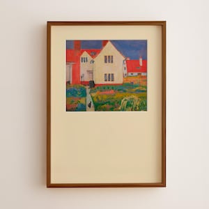 Puede incluir: Obra de arte enmarcada que representa un paisaje colorido con casas y un jardín. Las casas tienen tejados rojos y paredes blancas. Un gato negro camina por un camino. La obra de arte está en un marco de madera marrón.
