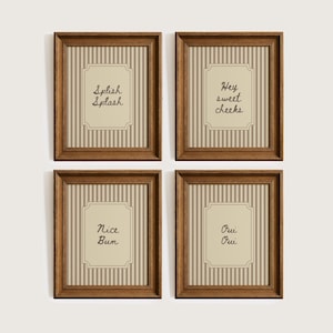 May include: Four framed prints with brown wooden frames. Each print has a beige background with vertical stripes and a central label with text. The text on the prints reads "Splish Splash", "Hey sweet cheeks", "Nice Bum", and "Oui Oui".