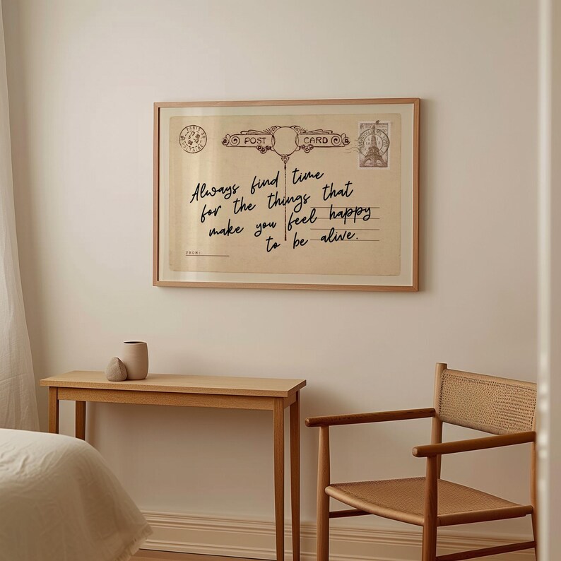 Puede incluir: Una impresi&oacute;n enmarcada que se asemeja a una postal vintage, con el texto "Always find time for the things that make you feel happy to be alive." La impresi&oacute;n se muestra sobre una mesa de madera y una silla tejida.