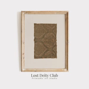 May include: A framed print of a brown and beige patterned fabric with a white mat and a light wood frame. The print is titled "Lost Deity Club Printable Art Studio".