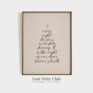 Könnte beinhalten: Gerahmter Druck mit goldfarbenem Rahmen. Das Kunstwerk zeigt den Text "O holy night! The stars are brightly shining. It is the night of our dear Savior's birth" in Form eines Weihnachtsbaums. Die Worte "Lost Deity Club Printable Art Studio" stehen unten.