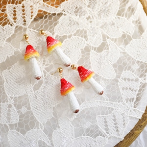 May include: A pair of mushroom-shaped earrings with red, yellow, and white details. The earrings are made of beads and have gold-colored hooks.