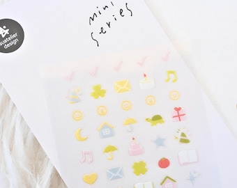 May include: A sheet of colorful stickers with various icons, including a house, a turtle, a musical note, and a heart. The stickers are in pastel colors and are arranged on a white background. The words "mini series" are written at the top.