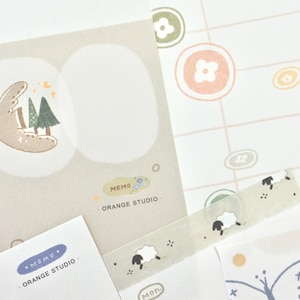 May include: A collection of stationery items featuring a whimsical design. Includes memo pads with a moon and tree illustration, patterned paper, and a tape with sheep. The text "MEMO ORANGE STUDIO" is visible.