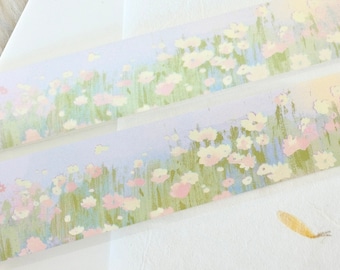 May include: Two rolls of washi tape with a floral design. The tape features a light blue background with pink and white flowers and green leaves.