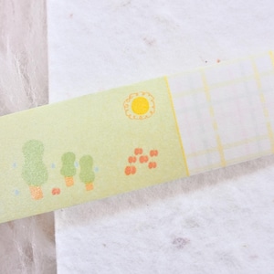 May include: Washi tape with a repeating pattern of a sunny day scene. The tape has a light green background with illustrations of trees, a sun, and other elements. Ideal for scrapbooking, journaling, and crafts. The tape is measured in centimetres.