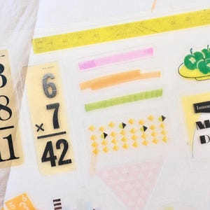 May include: A white ceramic mug with a black handle and the text "But First, Coffee" in a bold, black font. The mug is set against a neutral background, highlighting its simple design.