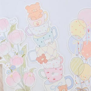 May include: Three die-cut stickers featuring pastel illustrations: a bouquet of pink tulips with small white rabbits, a vertical stack of five patterned teacups with small teddy bears, and a cluster of five colorful balloons with ribbons.