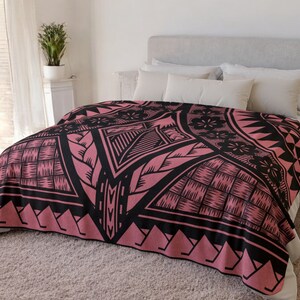 Puede incluir: Una manta de tiro de color rosa y negro con un dise&ntilde;o geom&eacute;trico. La manta est&aacute; hecha de tela suave y mullida y presenta un motivo tradicional polinesio.