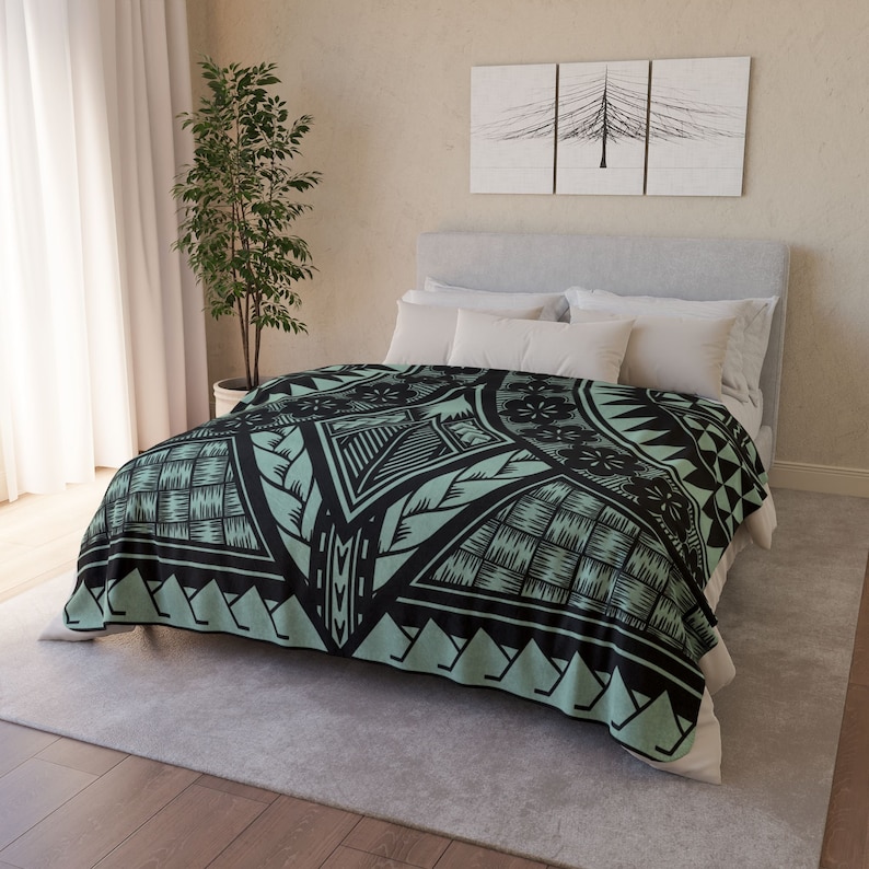 Puede incluir: Una manta de franela con estampado geom&eacute;trico verde y negro. La manta est&aacute; sobre una cama con almohadas blancas.