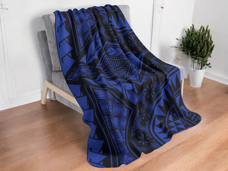 Puede incluir: Una manta de forro polar azul y negro con un dise&ntilde;o geom&eacute;trico. La manta est&aacute; colocada sobre un sof&aacute; gris.