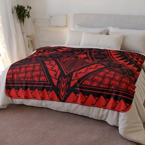 Puede incluir: Manta de forro polar roja y negra con un dise&ntilde;o geom&eacute;trico. La manta est&aacute; sobre una cama blanca con almohadas blancas.