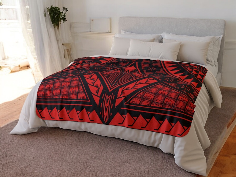 Puede incluir: Manta de forro polar roja y negra con un dise&ntilde;o geom&eacute;trico. La manta est&aacute; sobre una cama blanca con almohadas blancas.