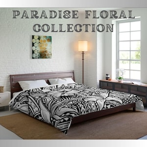 May include: Black and white patterned duvet cover with a floral design. The duvet cover is on a bed with white pillows and a wooden frame. The text "PARADISE FLORAL COLLECTION" is at the top of the image.