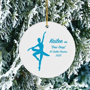 May include: White ceramic Christmas ornament with a blue silhouette of a ballerina. The ornament reads "Kailee as "Dew Drop" KC Ballet Theatre 2023".