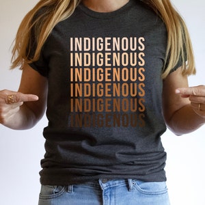 Może przedstawiać: Szary t-shirt z napisem "Indigenous" powt&oacute;rzonym sześć razy w gradiencie brązowych odcieni.