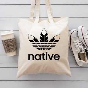 May include: A white canvas tote bag with black handles and a black graphic of a stylized leaf with the word "native" printed below it.