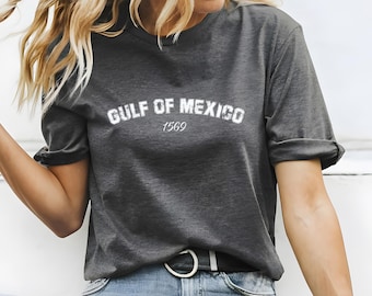 May include: A dark gray t-shirt with a white graphic that says "GULF OF MEXICO 1569".