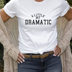 May include: White t-shirt with black text that reads "A Little Bit Dramatic".