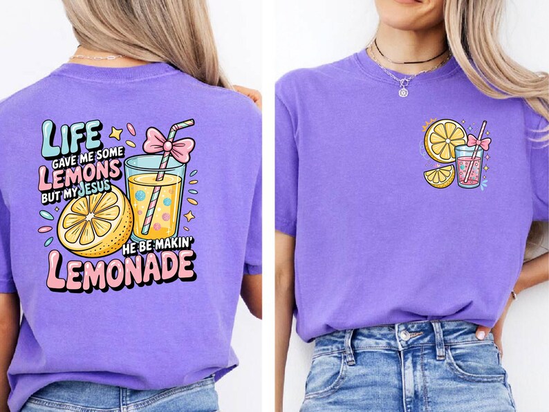May include: Purple t-shirts with lemonade-themed graphics. One shirt features a large graphic on the back with text and a lemonade glass. The other shirt has a smaller lemonade graphic on the front. Both shirts have a crew neck.