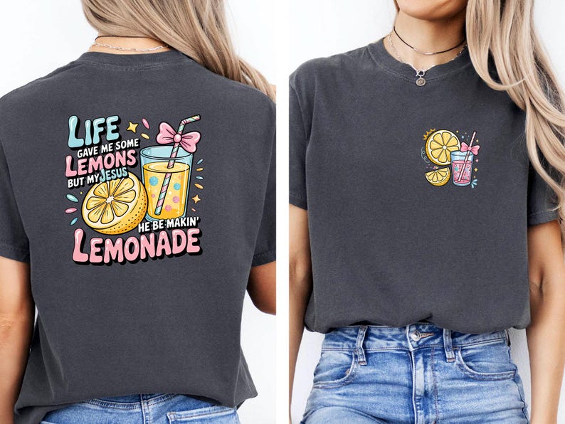 May include: Dark gray t-shirt with a colorful graphic on the back that says "Life gave me some lemons but my Jesus he be makin' lemonade." The design includes a lemon, a glass of lemonade, and a pink bow. A smaller version of the design is on the front.