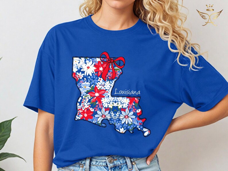 May include: A royal blue t-shirt with a floral design of the state of Louisiana. The design includes a red bow and the word "Louisiana".