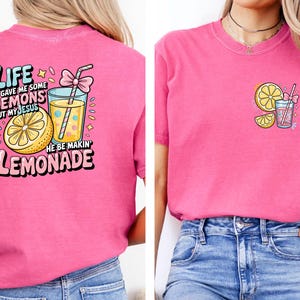 May include: A pink t-shirt with a graphic design featuring a lemon, a glass of lemonade, and the text "Life gave me some lemons but my Jesus he be makin' lemonade."