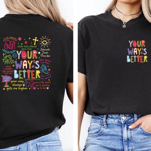 May include: Black t-shirt with colorful text and graphics. The front of the shirt has the text "YOUR WAY'S BETTER" in a rainbow design. The back of the shirt has additional text and graphics, including the words "Jesus Way".