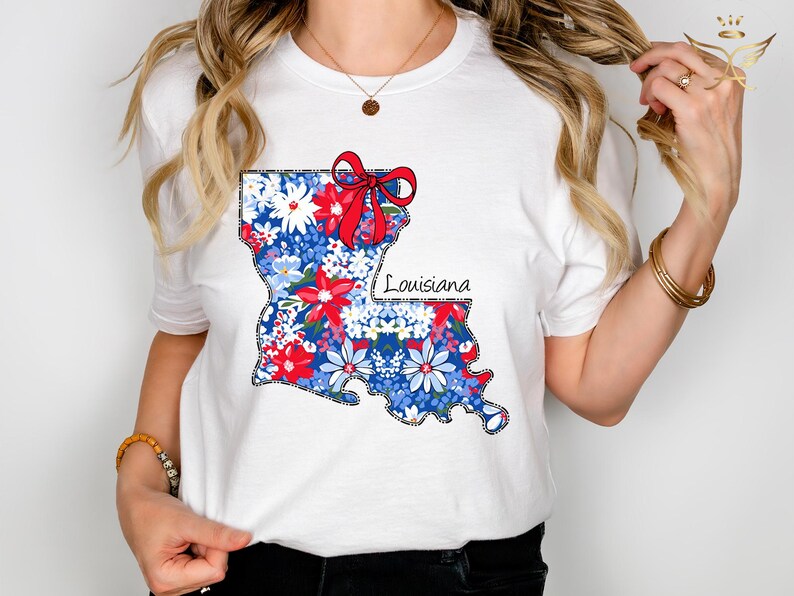 May include: White t-shirt with a floral print of the state of Louisiana. The print includes a red bow and the word "Louisiana".