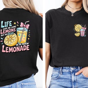 May include: Black t-shirt with a colorful graphic on the back that says "Life gave me some lemons but my Jesus he be makin' lemonade." The front has a smaller graphic of a lemon slice and a drink.