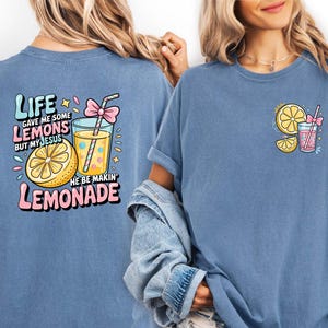 May include: Blue t-shirts with lemonade-themed graphics. One shirt features a large design on the back with text that reads "Life gave me some lemons but my Jesus he be makin' lemonade." The other shirt has a smaller design on the front.