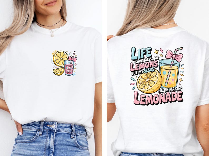 May include: White t-shirt featuring a colorful graphic of a lemon, lemonade, and the text "Life gave me some lemons but my Jesus he be makin' lemonade." The design includes pink, yellow, and blue accents. The shirt is a casual wear item.