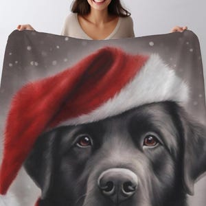 May include: A black Labrador Retriever wearing a red and white Santa hat. The dog is looking directly at the viewer with a serious expression. The background is a light gray with a subtle snowfall effect.