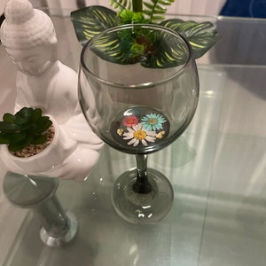 透明な黒いマグカップ。本物の押し花、プリザーブド バラの花びら、本物の野花が入ったワイングラス、手作りのパーソナライズされたグラス。