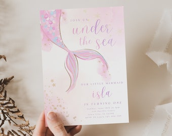 Può includere: Un'illustrazione di coda di sirena rosa e viola con stelle dorate scintillanti su uno sfondo bianco. Il testo "Join us under the sea" è in viola e il testo "Our little mermaid Isla is turning one" è in viola e rosa. L'invito include la data, l'ora, l'indirizzo e le informazioni RSVP.