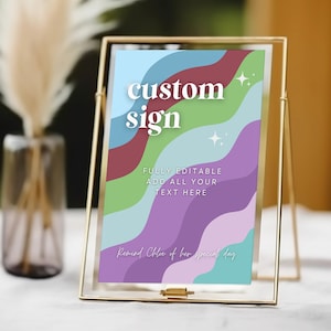 Puede incluir: Un marco dorado con un letrero colorido en su interior. El letrero tiene un diseño ondulado con colores morado, azul, verde y rojo. El texto en el letrero dice "custom sign" y "FULLY EDITABLE ADD ALL YOUR TEXT HERE Remind Chloe of her special day".