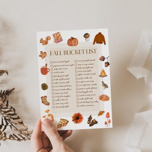 May include: A printable fall bucket list with illustrations of autumnal items like pumpkins, acorns, and leaves. The list includes activities like carving a pumpkin, making a pie, and decorating for fall.