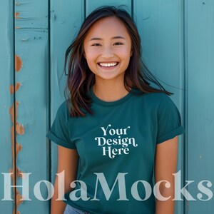 May include: A young person wearing a teal green t-shirt with the text "Your Design Here" printed on the front. The person is standing in front of a teal blue wooden wall.