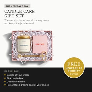 a gift set called "The Keepsake Box Candle Care Gift Set" presented in a pink box with white paper lining. The gift set includes a candle, a wick trimmer, a gold candle box, and a personalized greeting card.