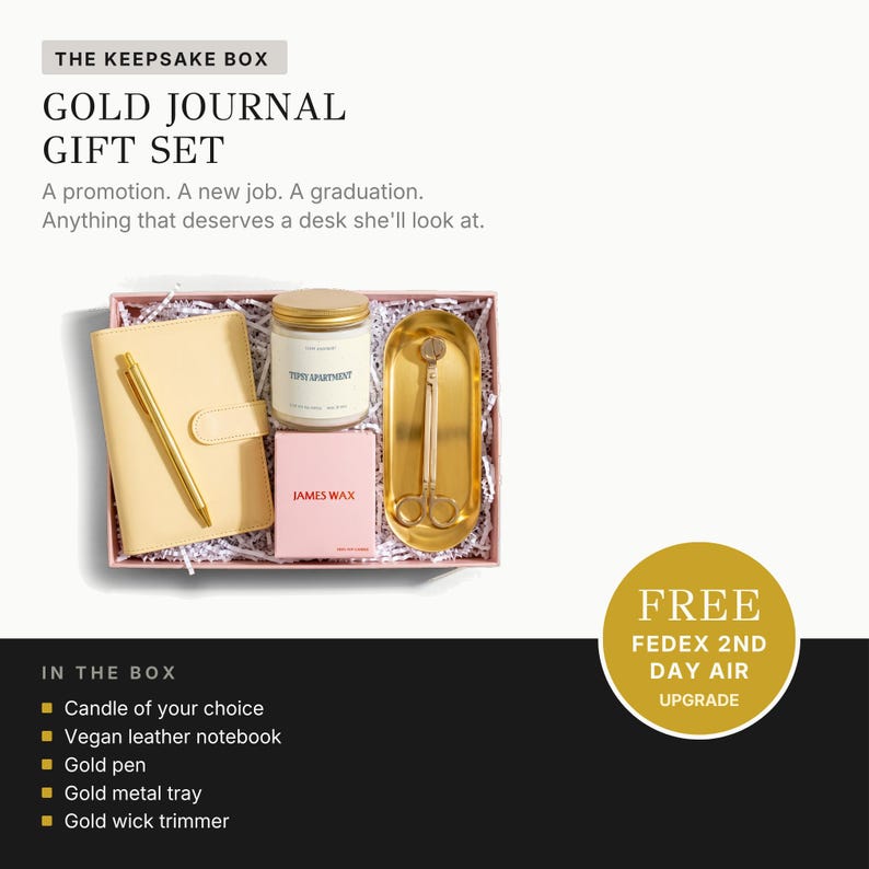 a gift set from The Keepsake Box, including a gold journal, a candle, a pen, a leather notebook, a gold pen, a gold metal tray, a gold wick trimmer, and a gold wick trimmer.