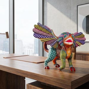 May include: A multi-coloured alebrije sculpture featuring a mythical creature with large wings, a wide open mouth with visible teeth, and intricate geometric patterns in shades of orange, green, purple, yellow, and blue covering its entire body.